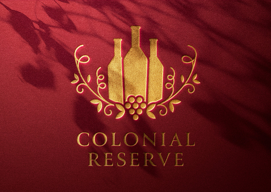 Luxury-style logo for ‘Colonial Reserve,’ featuring gold wine bottles and decorative vine elements, designed to convey a premium wine brand identity.